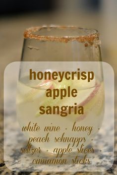 a glass filled with liquid sitting on top of a counter next to a sign that says honeycrisp apple sangria