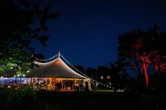 a tent is lit up at night with fairy lights on the roof and trees around it