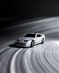 a white sports car driving on a black and white track with light swirling around it