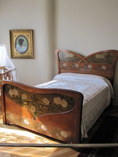 a bed sitting in the corner of a room next to a painting on the wall