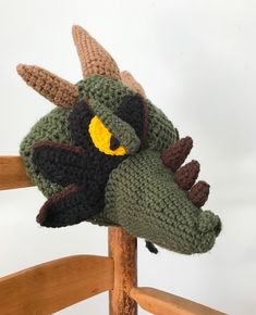 a crocheted hat with an animal's head on it sitting on top of a wooden chair