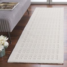 a white rug on top of a hard wood floor next to a couch and coffee table