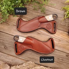 two brown leather sheaths sitting on top of a wooden table next to green plants