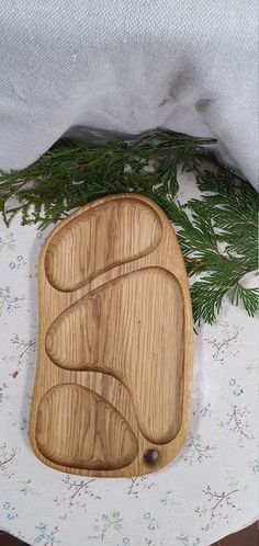 a wooden cutting board sitting on top of a table next to a white cloth and pine branches