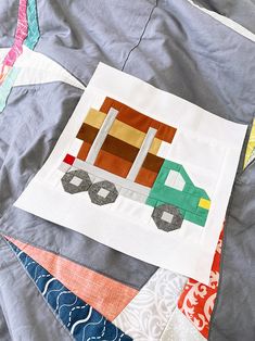 a close up of a patchwork quilt with a car on the front and side