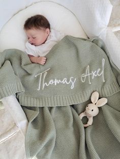 a baby wrapped in a blanket with the words thomas aged on it and a teddy bear