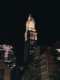 the tall building has a clock on it's side at night in the city