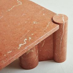 an orange marble table and two matching stools on a white surface with no one around it