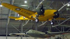 an airplane hanging from the ceiling in a hanger with other planes on it's sides