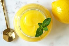 a glass jar filled with liquid next to an orange and a spoon on a marble surface