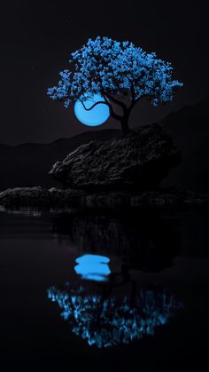 a blue tree sitting on top of a rock next to water