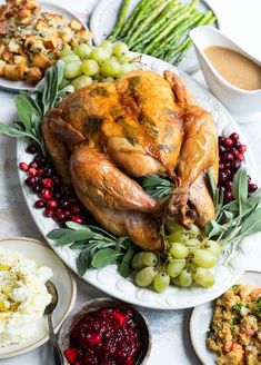 a turkey is sitting on a platter with grapes, stuffing and gravy