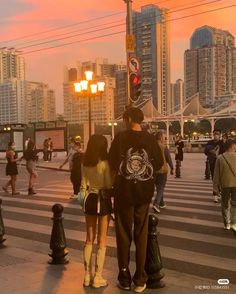 two people are standing on the crosswalk with their back to each other as they look at the city skyline