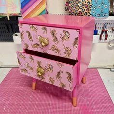 a pink and gold dresser sitting on top of a table