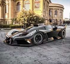 a black and gold sports car is parked in front of a large building on the street