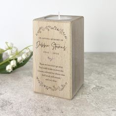 a small wooden box with a candle inside on a table next to some white flowers