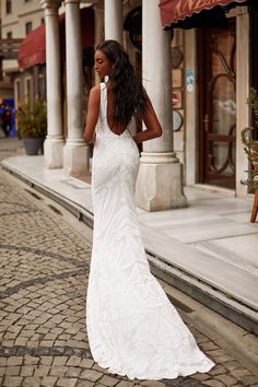 a woman in a white dress is walking down the street with her back to the camera