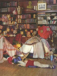 there is a person laying on the floor in front of a book shelf with many books