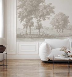 a living room with a white couch and wallpaper that has trees painted on it