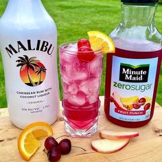 two bottles of lemonade, one with ice and the other with cherries are sitting on a wooden table