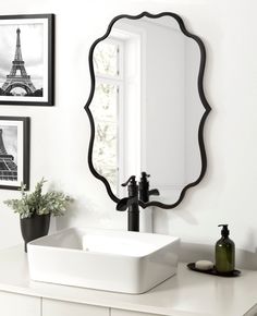 a bathroom sink with a mirror above it and pictures on the wall in front of it