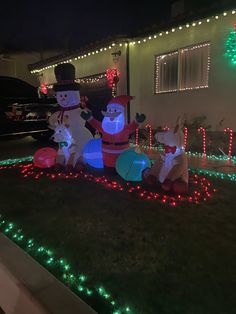 two snowmen in front of a house decorated with christmas lights