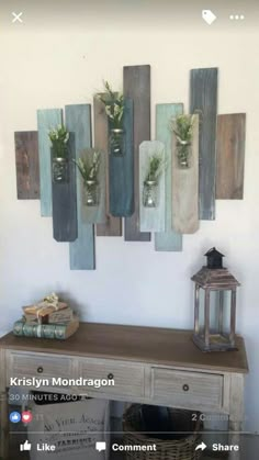 a wooden table topped with vases filled with plants next to a wall mounted art piece