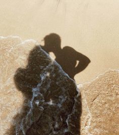 a shadow of a person standing on the beach