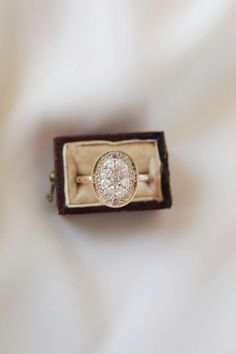 an engagement ring sitting in a box on top of a white cloth covered tablecloth