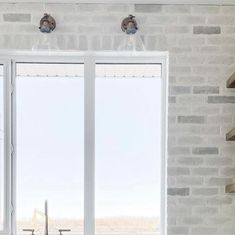 an open window in a white brick wall with shelves on either side and a sink below