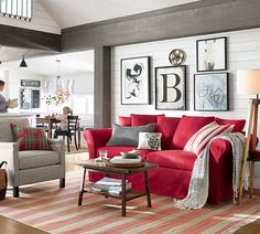 a living room with red couches and pictures on the wall above it's coffee table