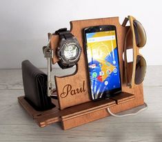 a wooden cell phone holder with sunglasses, watch and keychain on it's stand