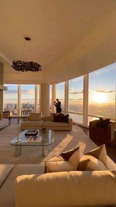 a living room filled with furniture and large windows overlooking the cityscape at sunset