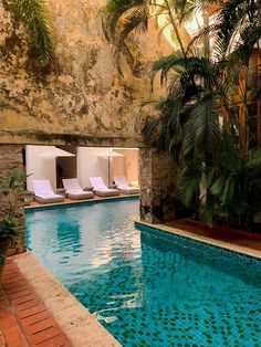 an indoor swimming pool with lounge chairs next to it