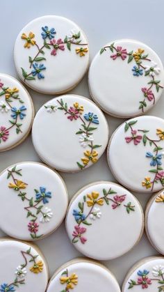 several decorated cookies sitting on top of a white table next to each other with flowers painted on them