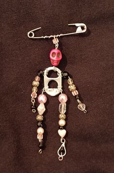 a pink and white beaded necklace with a skeleton charm hanging from it's side