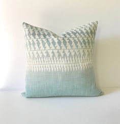 a blue and white pillow sitting on top of a white table next to a wall