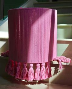 a pink lamp shade with tassels on it