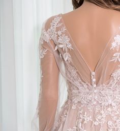 the back of a woman's wedding dress with sheer sleeves and floral appliques