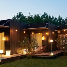 the outside of a house with lights on it and some trees in the back yard