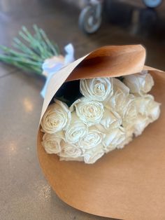 a bouquet of white roses wrapped in brown paper