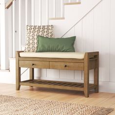 a wooden bench sitting under a stair case next to a green pillow on top of it