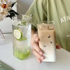 two people are holding glasses with drinks in them