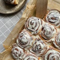 there are many cinnamon rolls on top of each other in the paper wrapper next to some plates