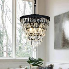 a chandelier hanging from the ceiling in a living room with white walls and windows