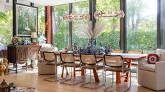 a dining room filled with lots of furniture and large windows overlooking the trees in the background