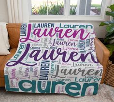 a couch with a personalized blanket on it in front of a window and potted plant