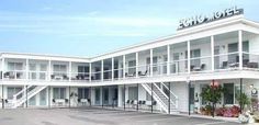 an empty parking lot in front of a motel with white balconies and flowers