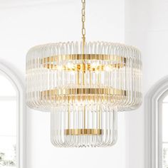 a chandelier hanging from the ceiling in a room with two windows and white walls