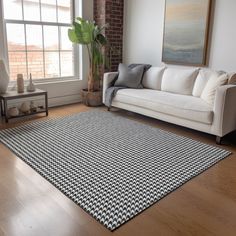 a living room with a white couch and black and white rug on the hardwood floor